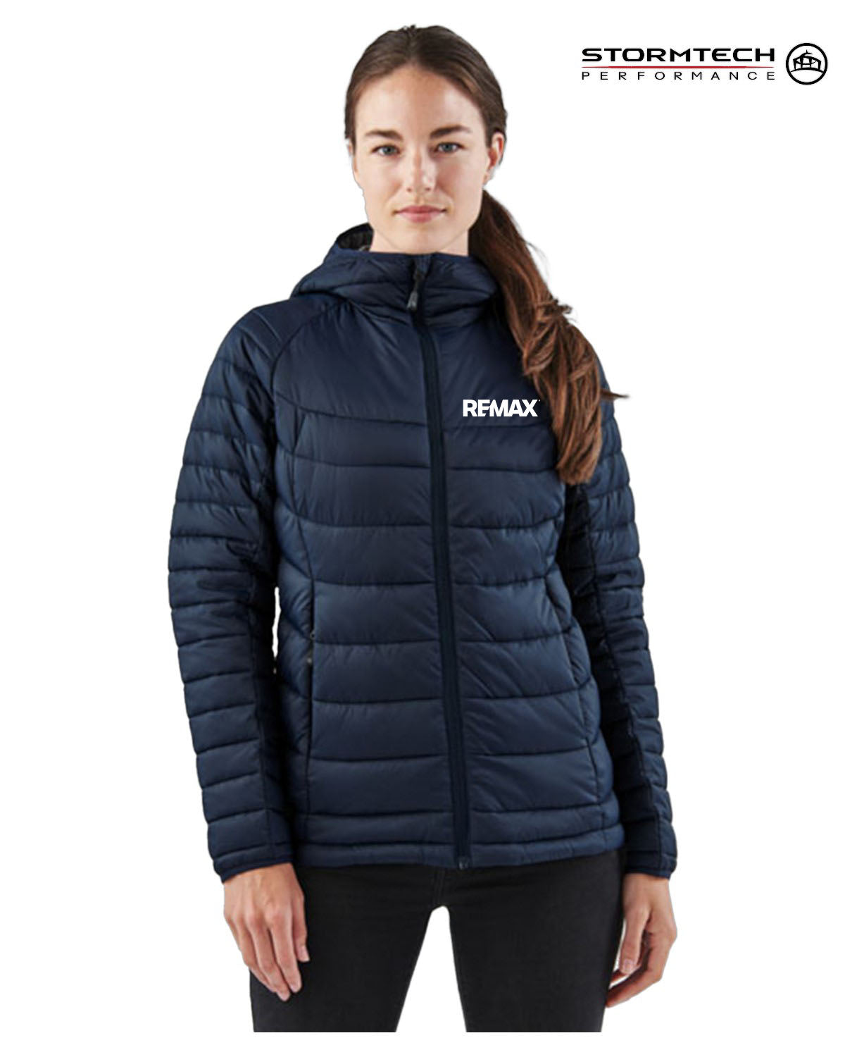 A woman wearing a navy blue Remax puffer jacket with a white logo on the chest, shown against a plain white background with a Stormtech Performance logo in the top right corner.