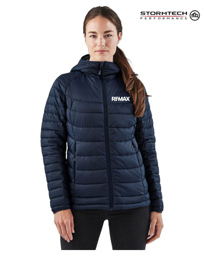A woman wearing a navy blue Remax puffer jacket with a white logo on the chest, shown against a plain white background with a Stormtech Performance logo in the top right corner.