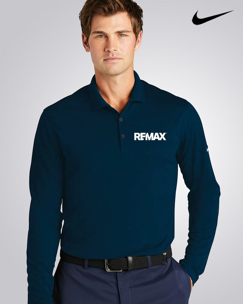 A man wearing a dark navy long-sleeve polo shirt with a white REMAX logo on the left chest, paired with navy pants and a black belt, against a light gray studio background with a black Nike swoosh in the top right corner.