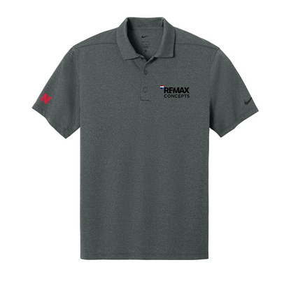 A dark heather gray short-sleeve polo shirt with a collar and two-button placket. The left chest features the black 'REMAX CONCEPTS' logo, the right chest has a small black Nike swoosh, and the right sleeve has a red Nike swoosh.