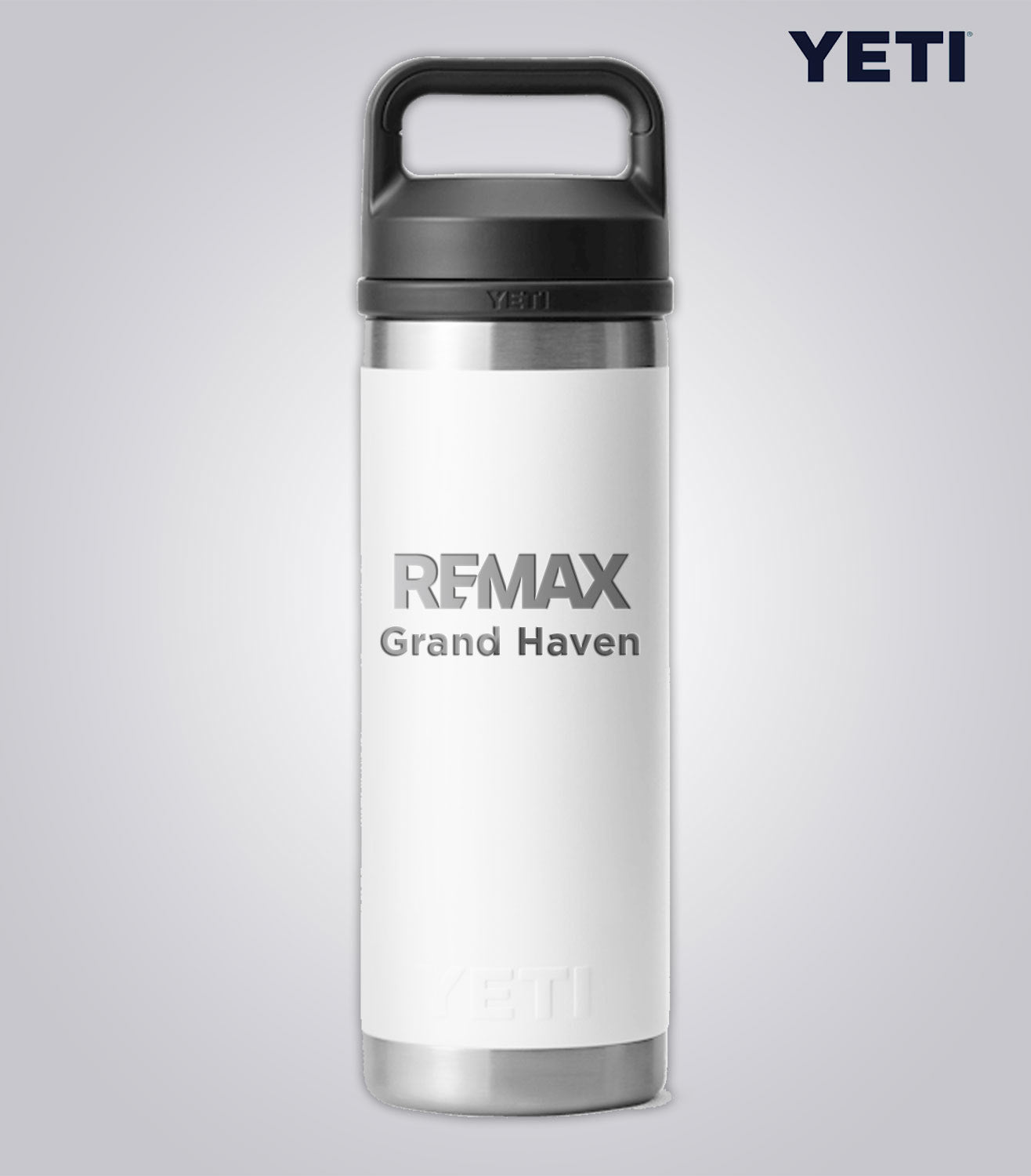 White YETI bottle with black lid featuring REMAX Grand Haven text on a light gray background