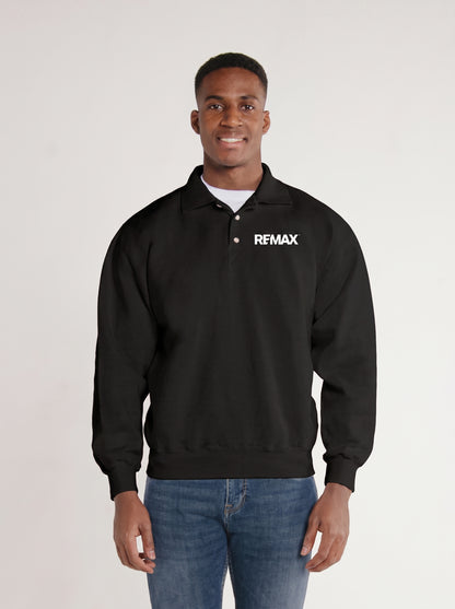 A man wearing a black long-sleeve polo-style sweatshirt with a white REMAX logo on the left chest, paired with blue jeans, standing against a light gray studio background.