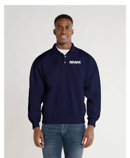 A man wearing a navy blue long-sleeve polo-style sweatshirt with a white REMAX logo on the left chest, paired with blue jeans, standing against a light gray studio background.