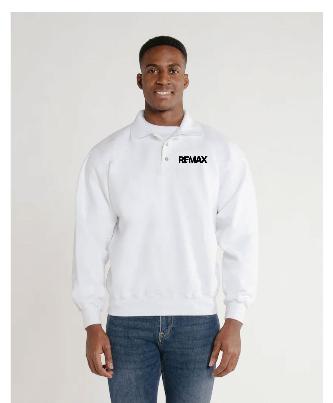 A man wearing a white long-sleeve polo sweatshirt with a black 'REMIX' logo on the chest, paired with blue jeans, standing against a light gray studio background.