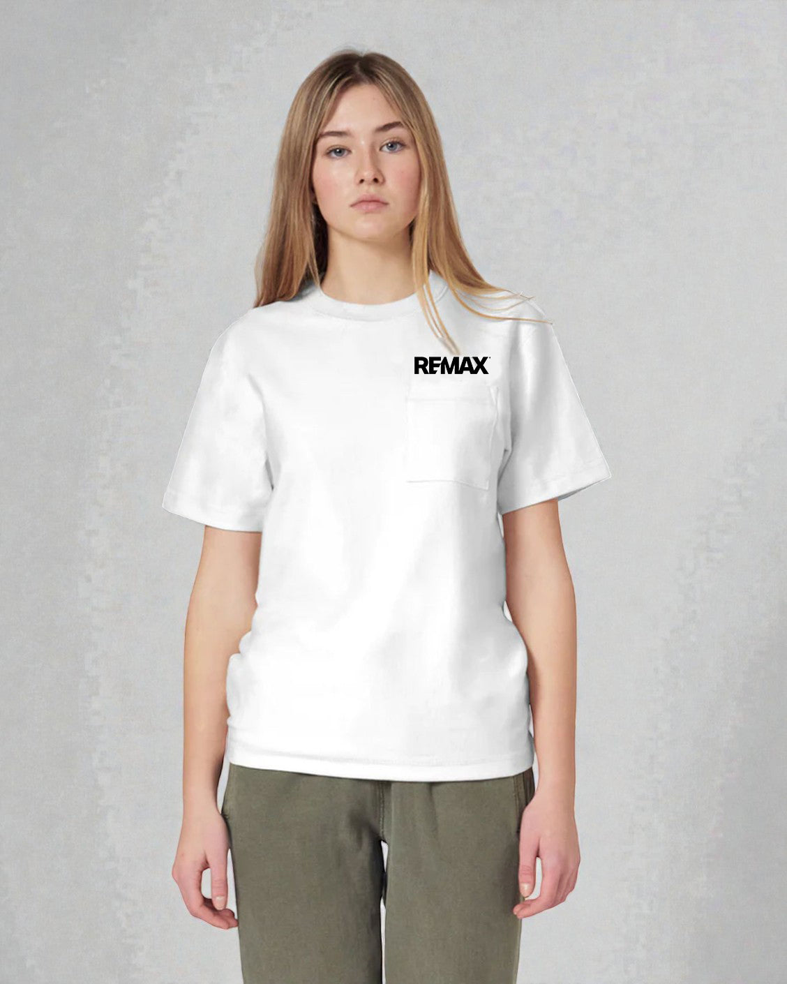 A woman modeling a white short-sleeve crewneck pocket t-shirt with a black 'REMAX' logo printed on the chest, paired with olive green pants, against a textured gray studio background.