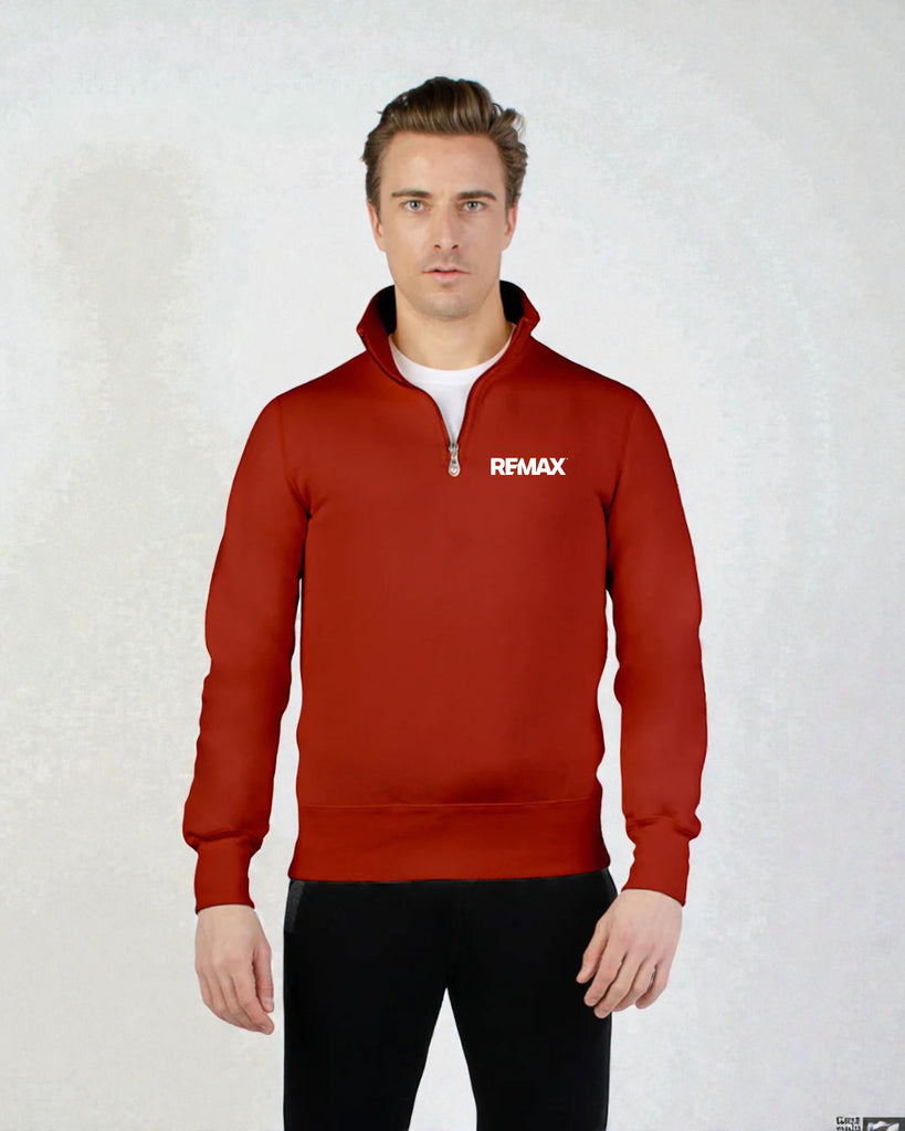A man wearing a red quarter-zip pullover sweatshirt with a white REMAX logo on the left chest, paired with black pants, standing against a light gray textured background.