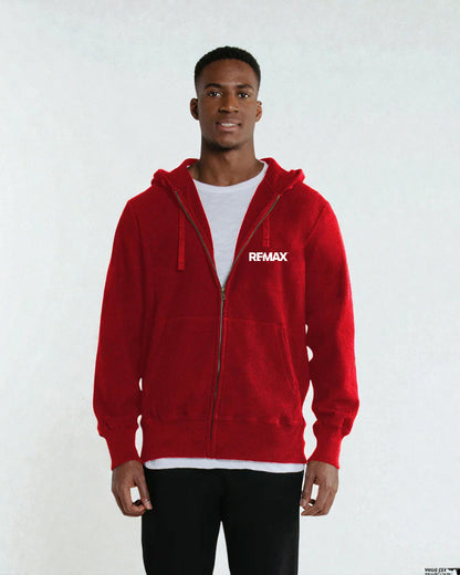 A man wearing a red zip-up hoodie with a white REMAX logo on the chest, layered over a white t-shirt and black pants, standing against a light gray background.