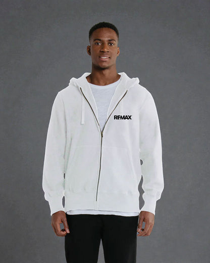 A man wearing a white zip-up hoodie with a black REMAX logo on the left chest, layered over a light gray t-shirt and black pants, standing against a textured gray studio background.