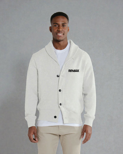 A man wearing a light cream-colored cardigan with a shawl collar, black buttons, and a black 'RFMAX' logo on the left chest, styled over a white t-shirt and beige pants against a gray studio background.
