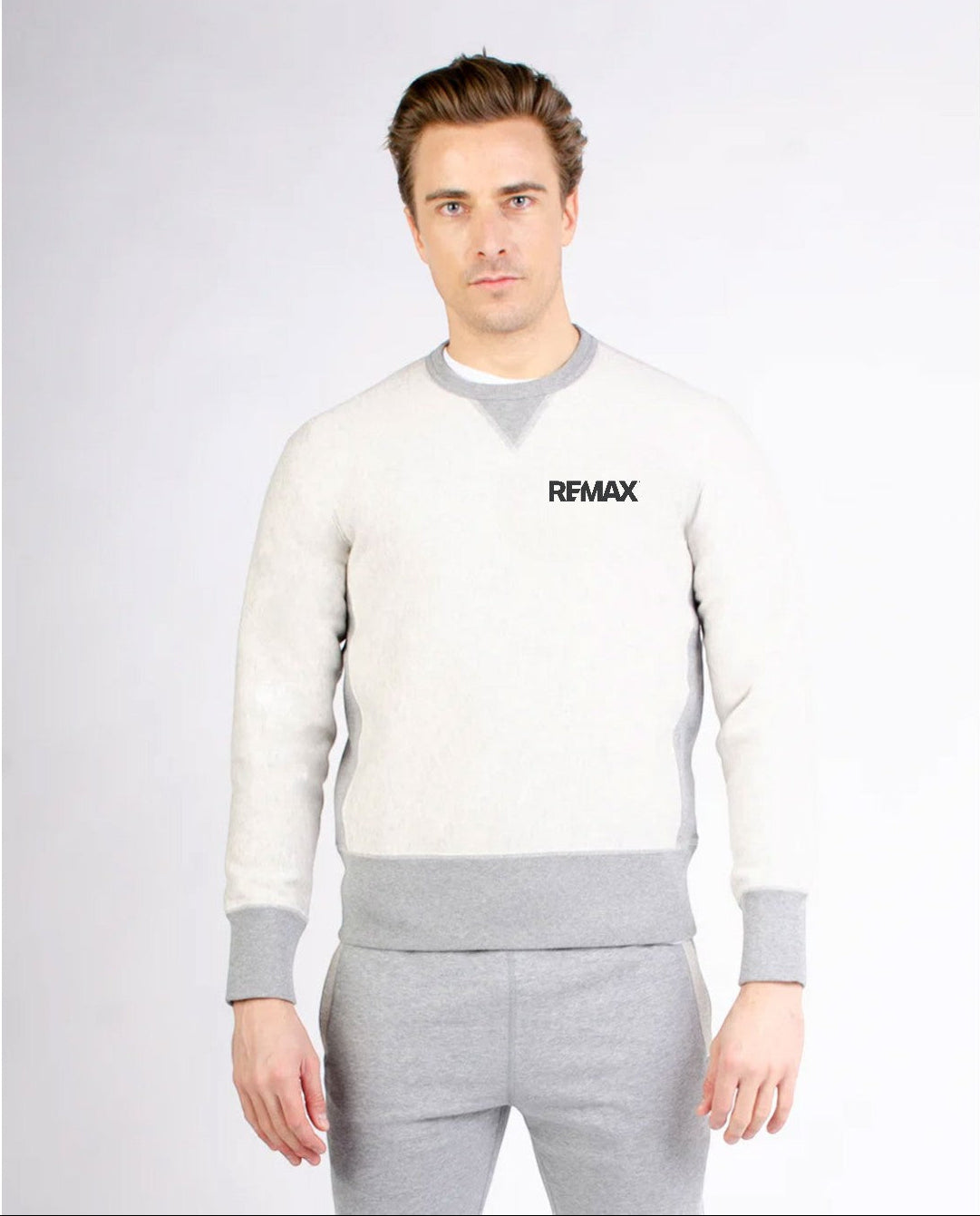 Man wearing a white and gray sweater with 'REMAX' logo on a light gray background