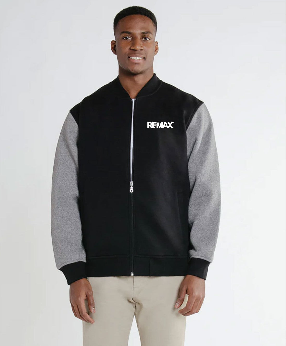 Man wearing a black and gray jacket with 'REMAX' logo on a white background