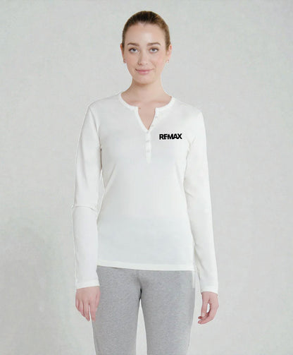 A woman modeling a white long-sleeve henley shirt with a small black REMAX logo on the left chest, paired with gray sweatpants, against a light gray textured studio background.