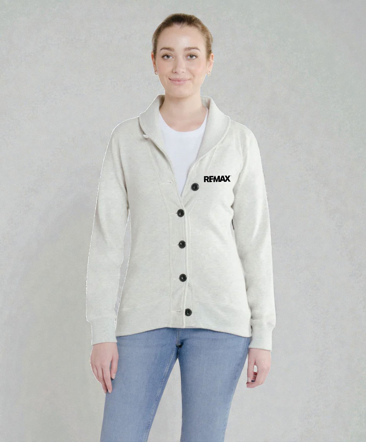 A woman modeling a light beige cardigan with black buttons and a black REMAX logo on the left chest, worn over a white t-shirt and blue jeans against a textured gray background.