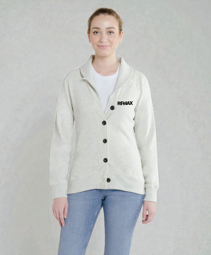 A woman modeling a light beige cardigan with black buttons and a black REMAX logo on the left chest, worn over a white t-shirt and blue jeans against a textured gray background.