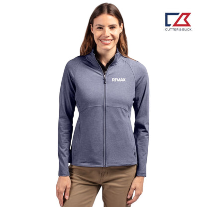 Woman wearing a blue jacket with a visible Remax logo on a white background, featuring the Cutter & Buck brand.