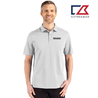Man wearing a gray polo shirt with REMAX logo, standing against a white background with Cutter & Buck logo.