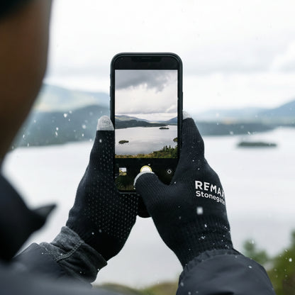 Black gloves with the REMAX Stonegate logo while holding a phone.