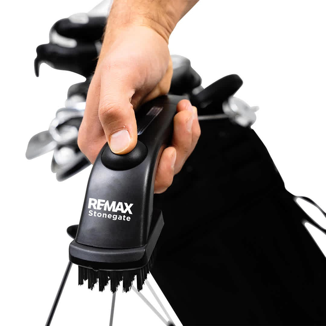 Hand holding a black grooming tool with 'Remax Stonegate' branding against a white background