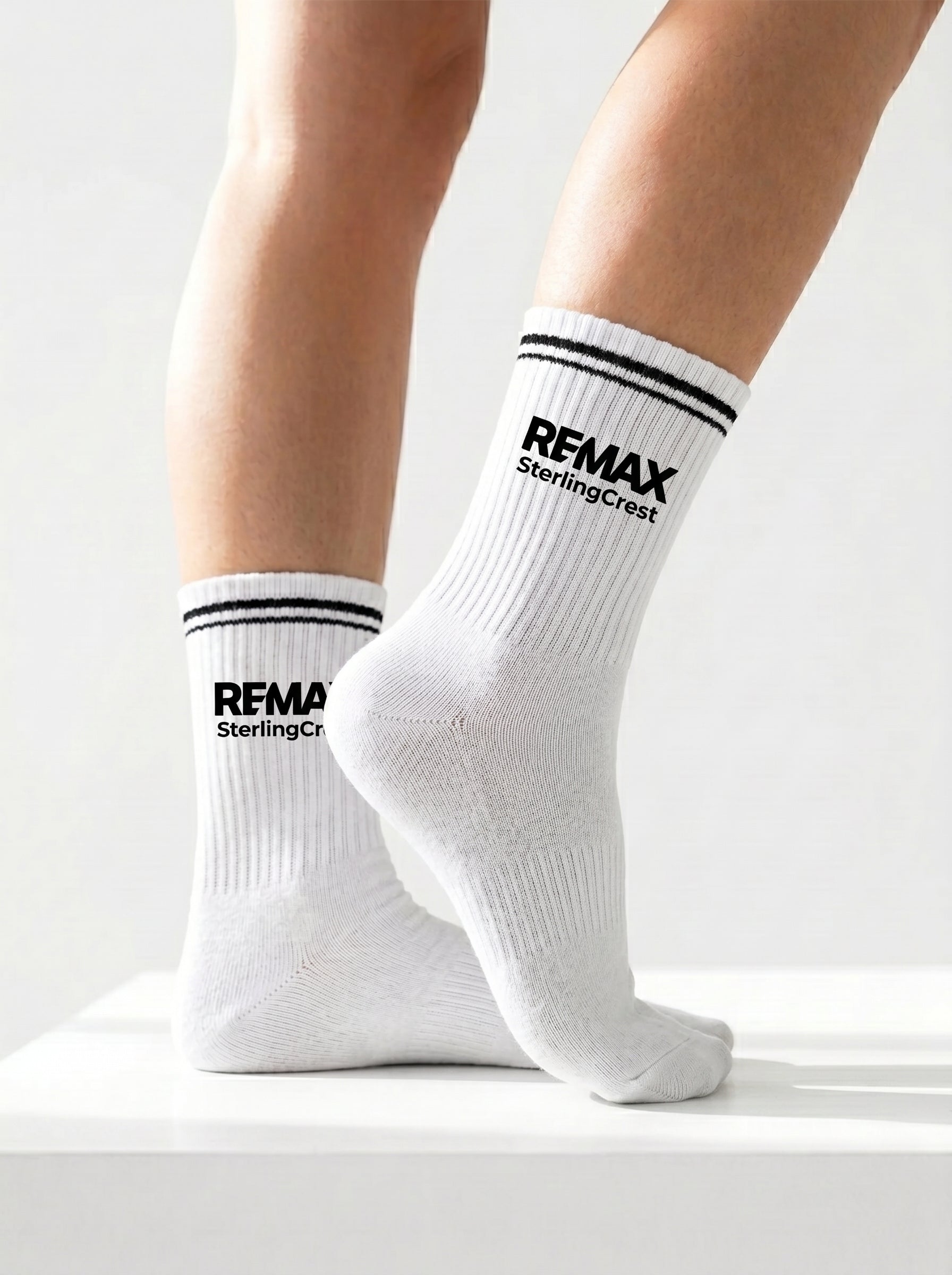 White socks with 'REMAX' branding worn by a person on a light gray background