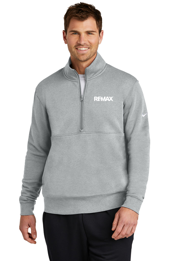 A man wearing a heather gray Nike quarter-zip pullover with a white REMAX logo on the chest and a white Nike swoosh on the sleeve, set against a plain white background.