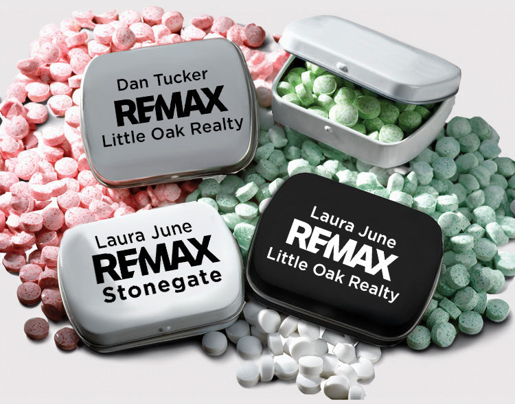 Three small tin containers with REMAX branding surrounded by colorful candies.