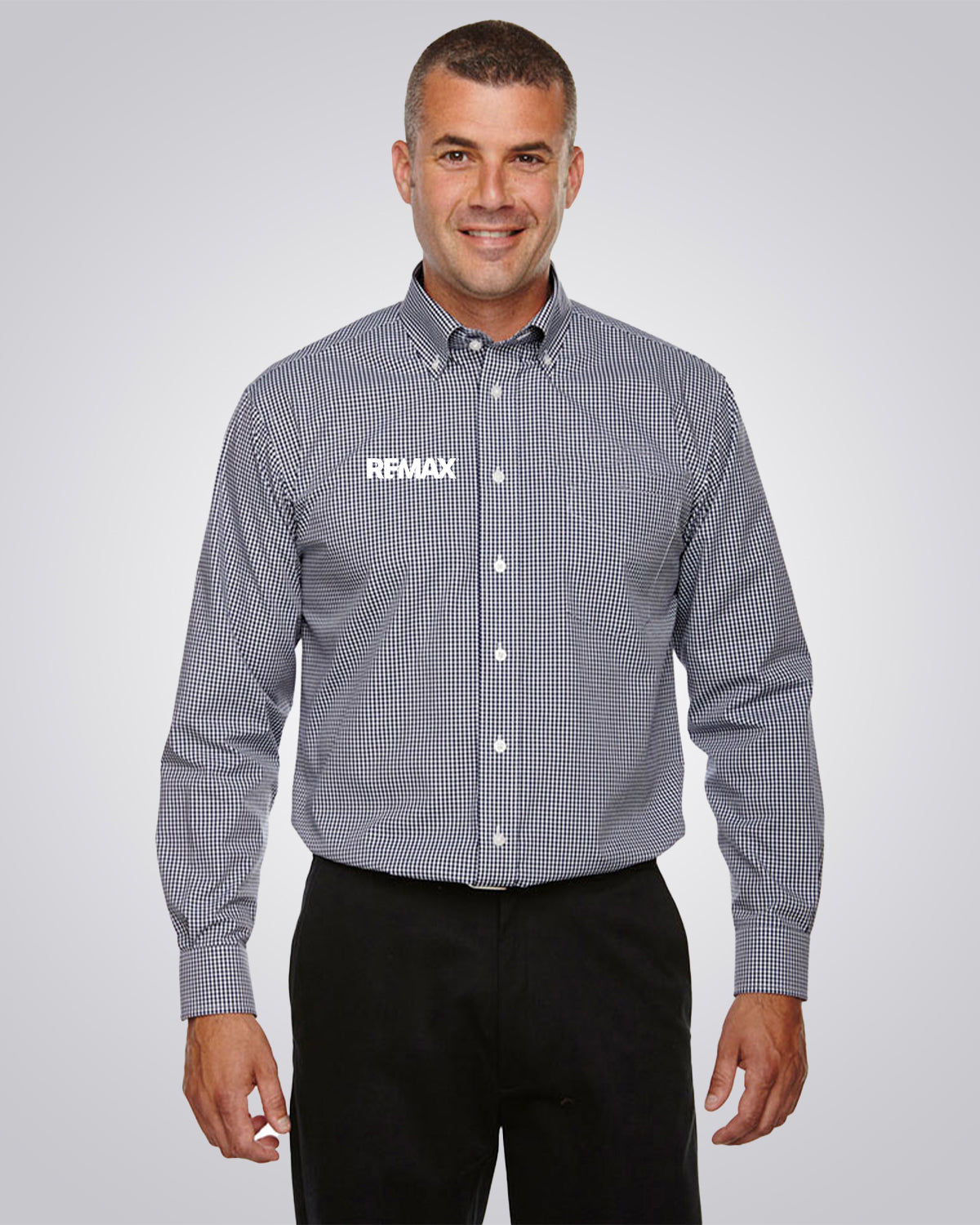 A man wearing a gray and white checkered button-down shirt with 'REMAX' printed in white on the left chest, paired with black pants, against a light gray studio background.
