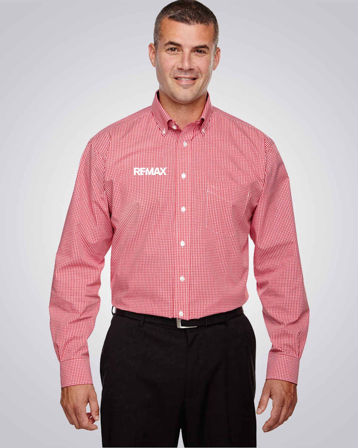 A man wearing a red and white checkered long-sleeve button-down shirt with the REMAX logo on the left chest, paired with black pants, against a light gray studio background.