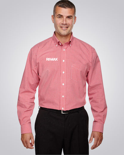 A man wearing a red and white checkered long-sleeve button-down shirt with the REMAX logo on the left chest, paired with black pants, against a light gray studio background.