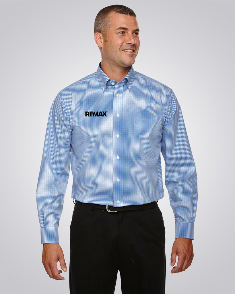 A man wearing a light blue and white micro-check patterned button-down shirt with a black REMAX logo on the left chest, paired with black pants, against a light gray studio background.