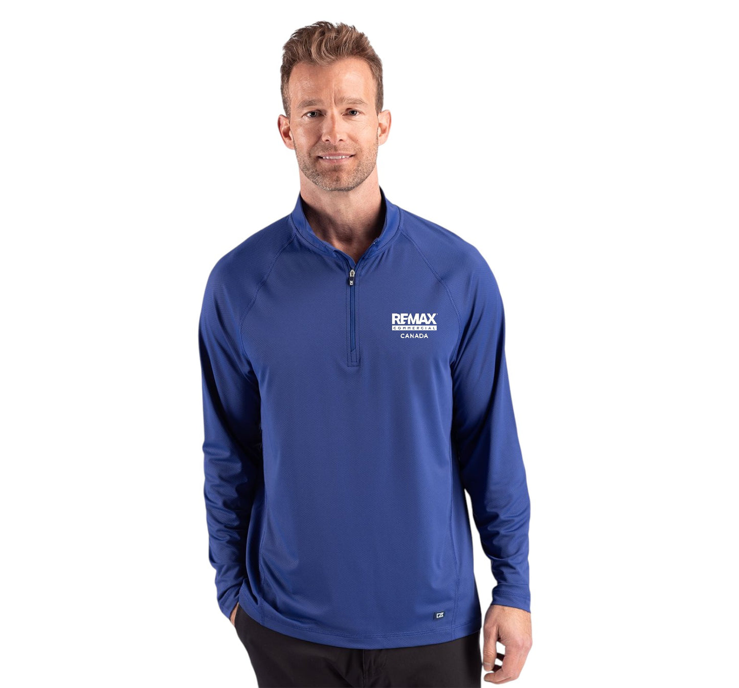 A man wearing a royal blue long-sleeve quarter-zip pullover with a white 'REMAX' logo on the left chest, photographed against a solid white background.
