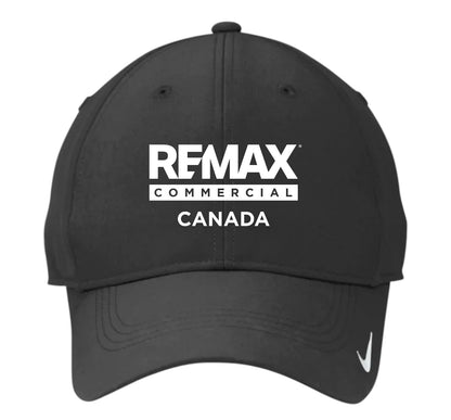 A black baseball cap featuring the white text 'REMAX COMMERCIAL CANADA' on the front and a small white Nike swoosh on the brim, set against a plain white background.